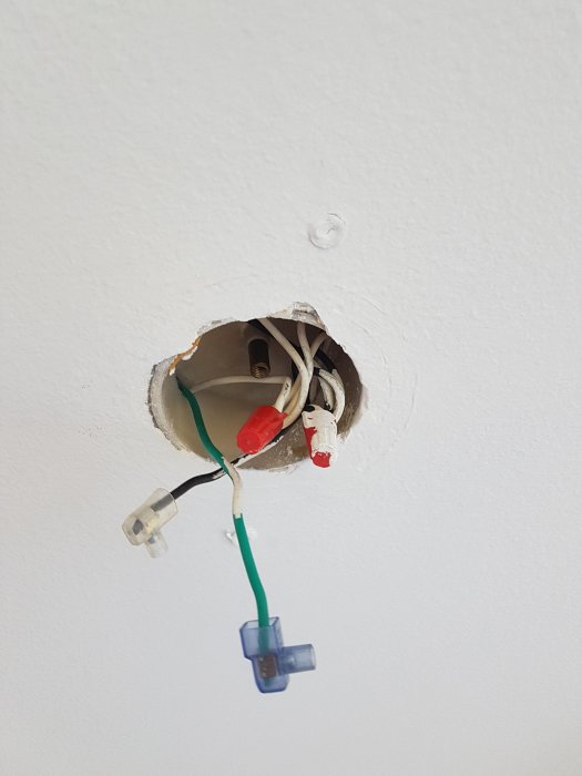 Elektriska kablar i taket med en svart och en blågrön sladd synliga, med osäkerhet kring deras användning.