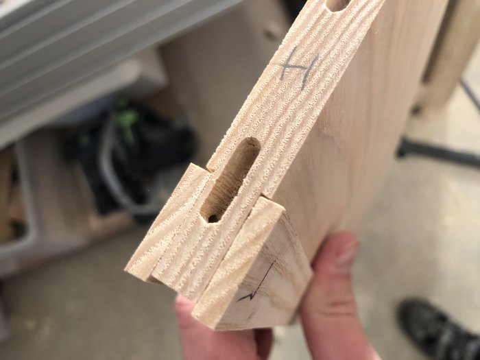 Hand håller trälister med synlig hyvlad kant och förborrade hål.