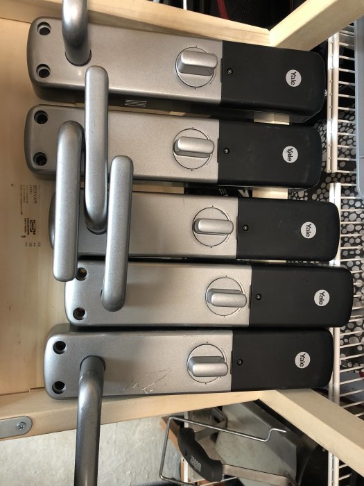 Fem Yale Doorman v2 elektroniska lås, vissa med skav och repor, utan batterier, lagrade på hylla.