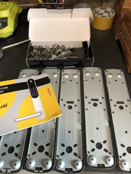 Fem Yale Doorman v2 elektroniska dörrlås utlagda på ett bord med en installationsmanual och en låda med skruvar.