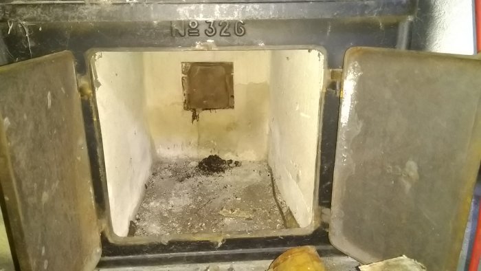 Insidan av en Kockums No. 326 vedspis med synlig nummer, aska och en liten, öppen lucka.