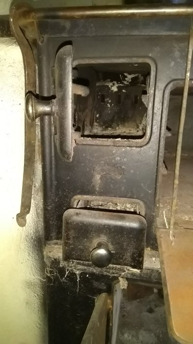 Närbild på en dammig, använd Kockums vedspis no. 326 med synliga reglage och en lucka för luftningskanalen.