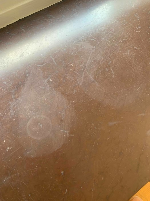 Närbild på en stenfönsterkarm med rispor och missfärgningar.