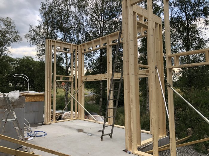 Pågående bygge av hög träväggstomme i ett framtida vardagsrum med planerad takhöjd på 4 meter.