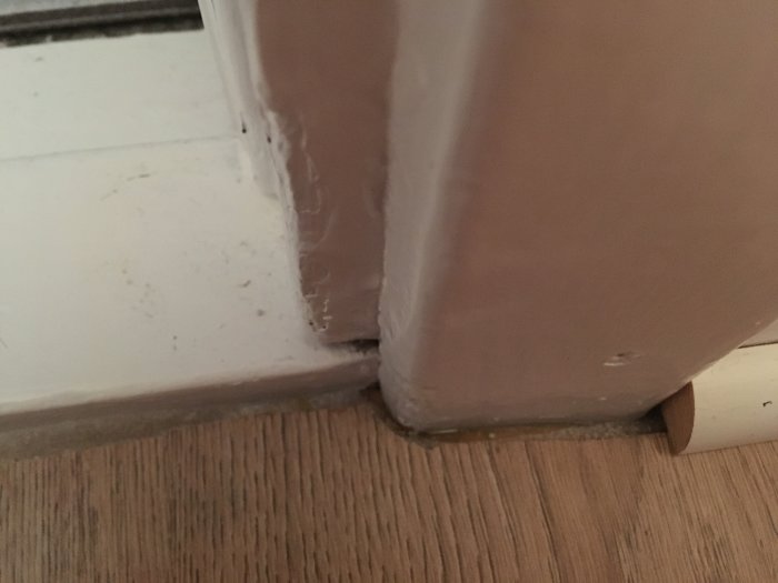 Kvartsstav placerad mot golvlist bredvid en ojämn dörrpost i en anslutning till trägolv.