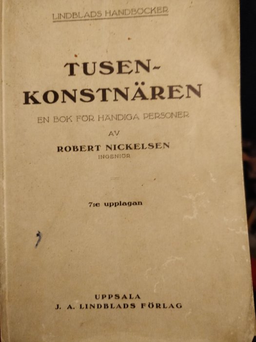 Sliten omslagssida av boken "TUSENKONSTNÄREN - EN BOK FÖR HANDIGA PERSONER" av Robert Nickelsen, 7:e upplagan.