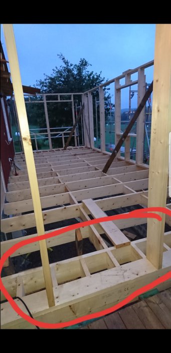 Konstruktion av träreglar och bjälkar i ett pågående byggprojekt vid skymning.