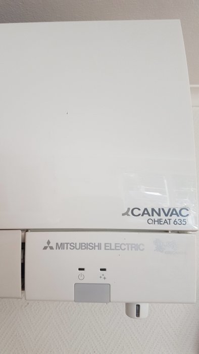 Värmepump av märket "Mitsubishi Electric" installerad på en vägg.