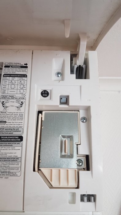 Inre panel av en väggmonterad enhet med varningstexter och en "E.O. SW" knapp.