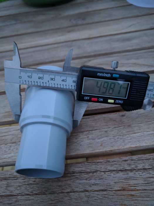 Skjutmått som mäter diameter på ett vitt rör visas på displayen: 49,87 mm.