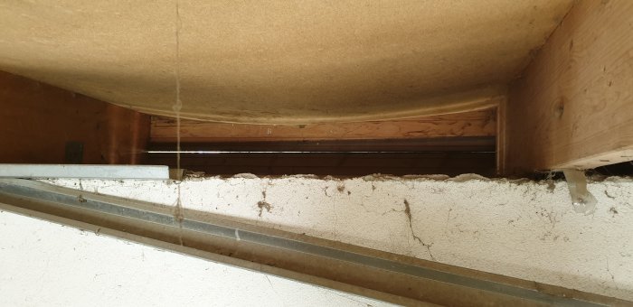 Takunderkonstruktion med lutande taksparrar på lecaväggar och en hängande masonitskiva ovanför.
