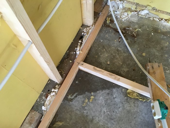 Renoveringsarbete i gillestuga, med rivet golv som avslöjar fukt och möjlig mögelskada vid syllarna.