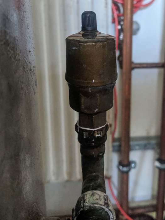 En säkerhetsventil till en hydrofor med en svart ventilhatt på toppen sittande på en rörledning.