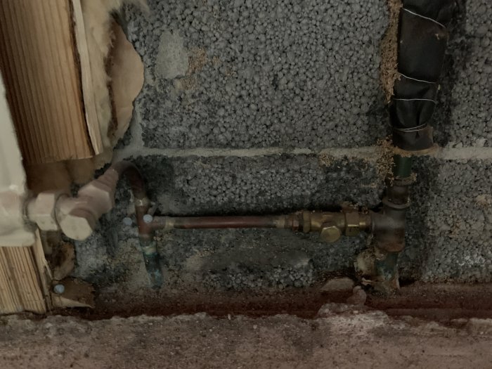Röranslutning med 17 mm stålrör och 12 mm kopparledning vid radiator i vägghål, med pålödd nippel och lekande mutter.