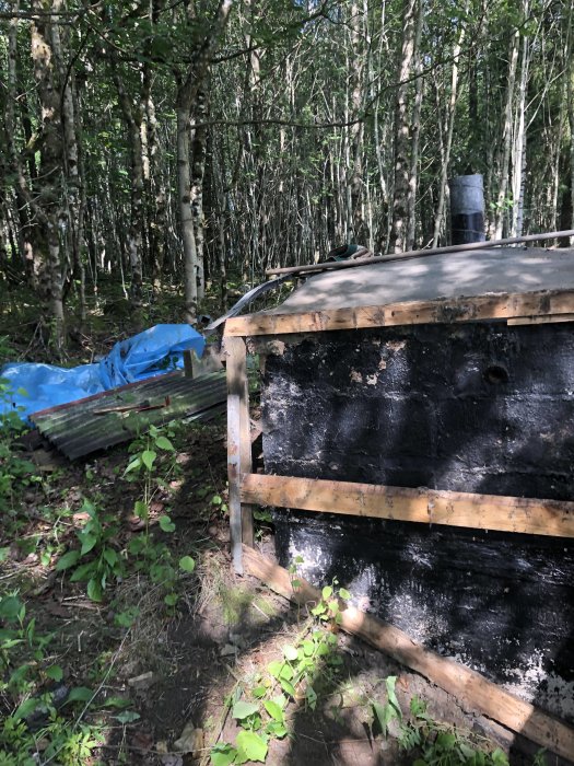 Renovering av en gammal murad matkällare med asfalttäckning, vid skogskant.