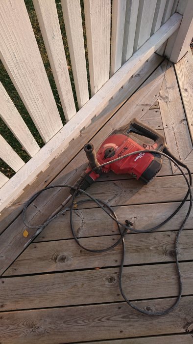 Stor Hilti borrhammare på ett trägolv ute på en veranda.