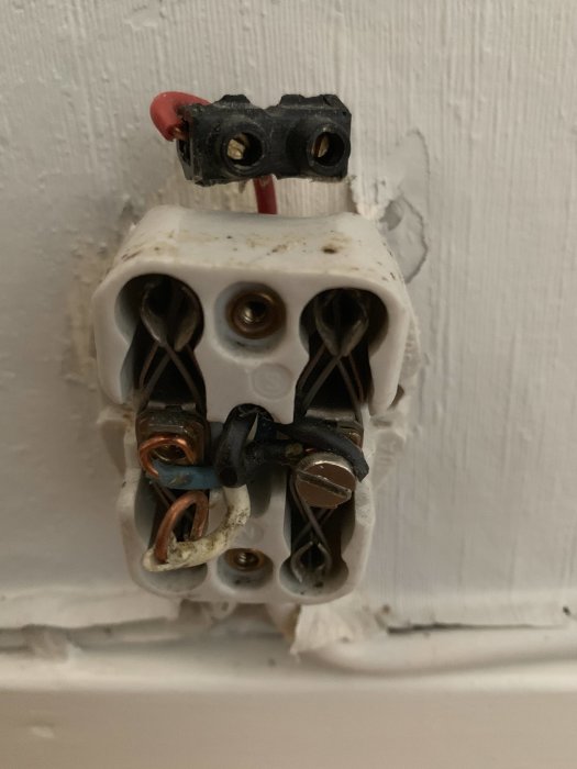 Öppen eluttag utan lock som visar anslutna kablar och elektriska kontakter mot en vit vägg.
