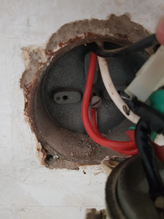 Elektriska kablar bakom en spis med en öppen anslutningsdosa och tre synliga ledare.