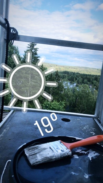 Utsikt från byggställning med målarpensel och hink, skog och sjö i bakgrunden, tecknad sol och 19 grader-visning.