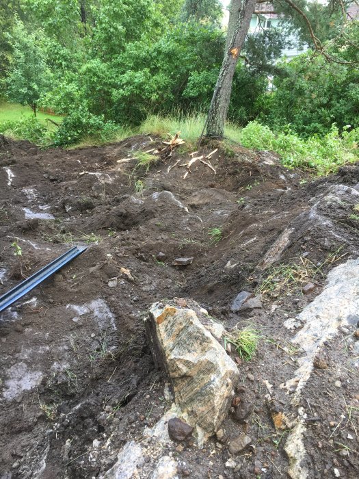 Nygrävd mark med synligt berg och jord för förberedelse av poolbygge.