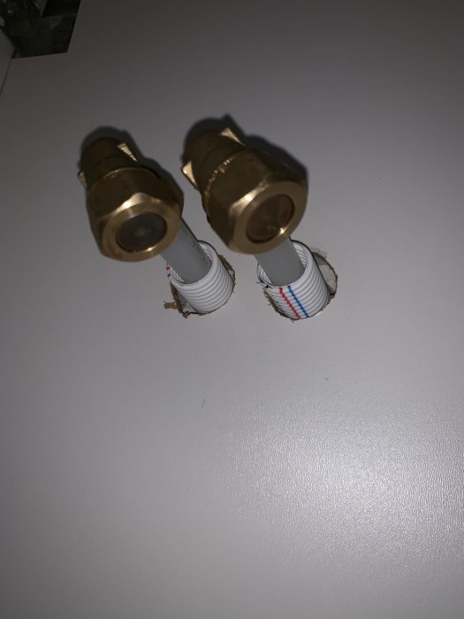 Två tillfälligt pluggade PEX-rör med påmonterade ballofixventiler som sticker ut från en vägg.