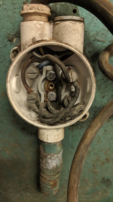 Gammal smärgels elektriska kopplingsdosaskådande sladdar och terminaler för byte av kontakter.