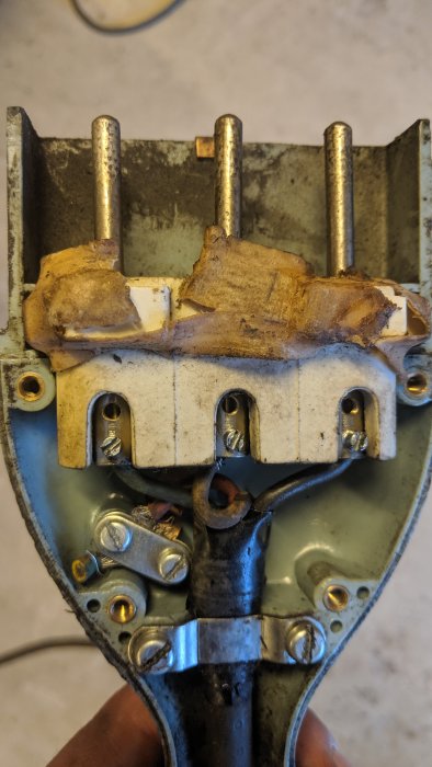 En bild på öppnad gammal semko-kontakt med synliga anslutningar och sladdar som är fästa vid anslutningsplintar.