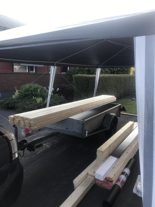 Träpanel lastad på släpvagn parkerad utomhus, risk för böjning i mitten.