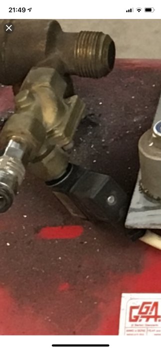 Magnetventil med kontaktstycke och spole i svart samt mässingsventil, på röd verktygsmatta.