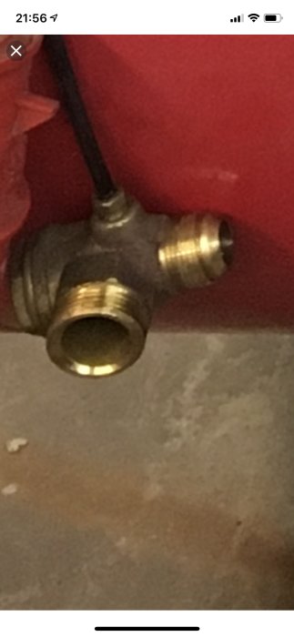 Tryckavlastningsventil med gängad del för anslutning till magnetventil, samt en svart luftslang, framför en röd bakgrund.