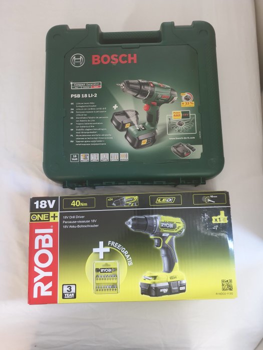 Bosch PSB 18 Li-2 och Ryobi R18DD2-113G skruvdragare i förpackningar ligger på ett bord.