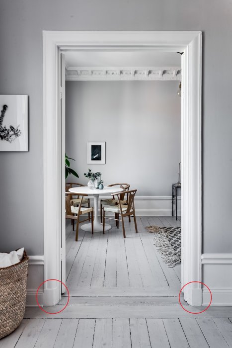 Elegant dörröppning till matrum med vitmålade dörrposter och detaljerad taklist, markerade delar vid golvet.
