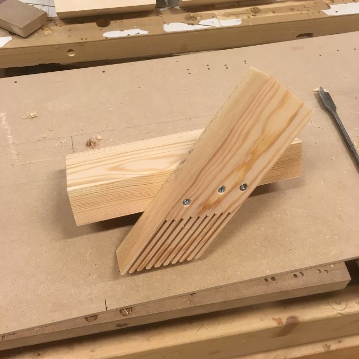 Träunderlag med spår för att stödja och såga kolfiberpaneler säkert, i verkstadsmiljö.