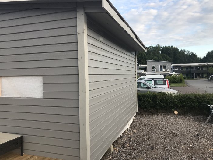 Hörnet på en nybyggd träkonstruktion med utvändig panel klart, med en obehandlad trädörröppning och fönsterutrymme.