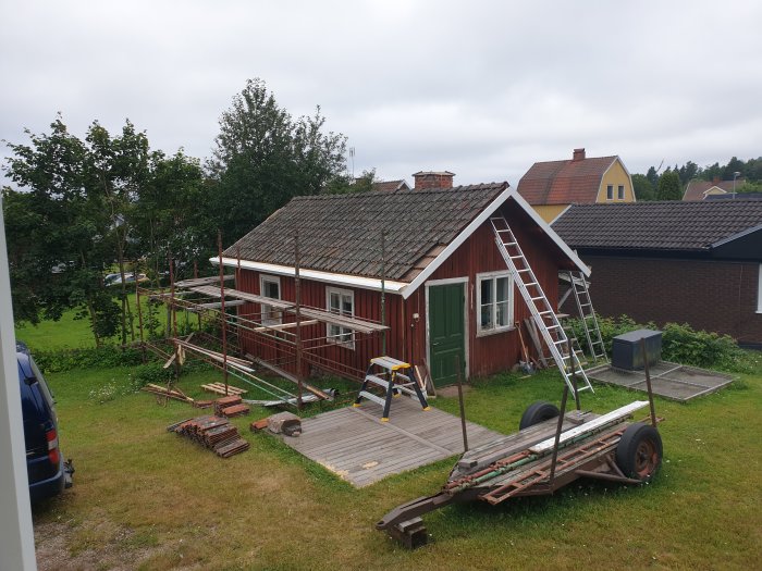 Renoveringsarbete på hus med ställning, nedtagna takpannor och en stege lutad mot taket.