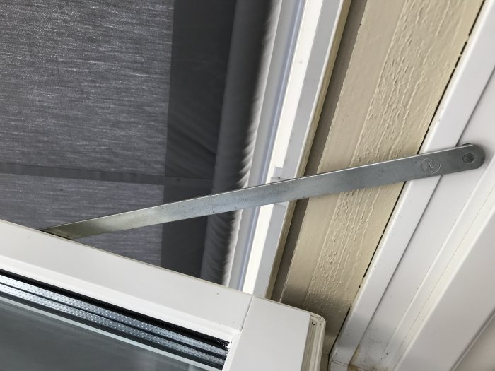 Altandörr med öppen fönsterbroms som visar låsmekanismen och handtaget.
