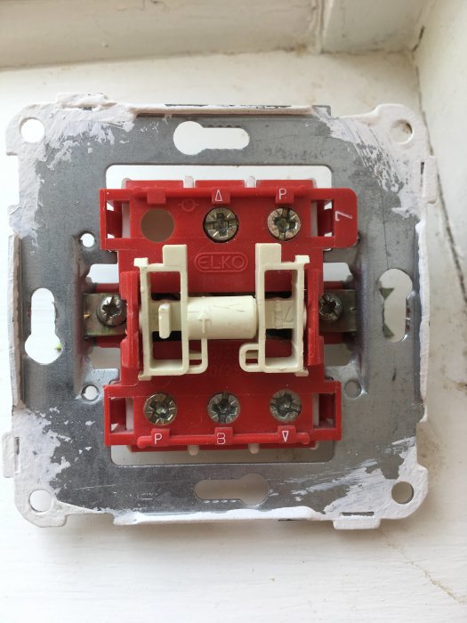 Röd och vit strömbrytare med fyra skruvanslutningar monterad på vägg, märkt med "ELKO".
