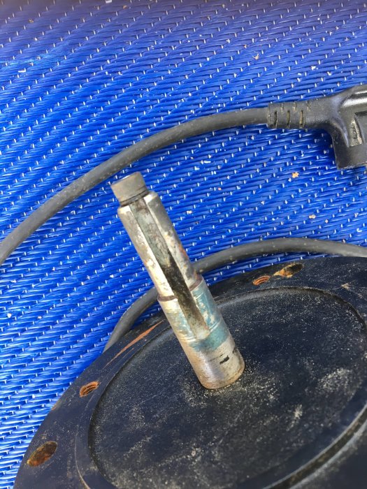 En uppmätt metallstång med diameter 17/14 mm som ligger på ett svart lock med en blå vävd bakgrund.