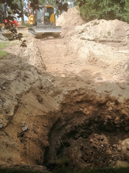 Brunnsgrävning i berg, grävmaskin ovanpå gropen, ungefär 6,5 meter djup med vattensippring.