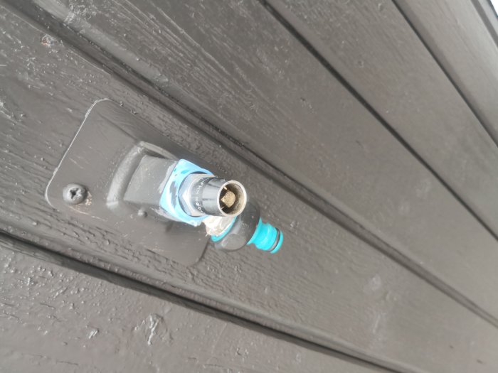 Vattenkopppling genom vägg med utstickande blå del och metallplatta.