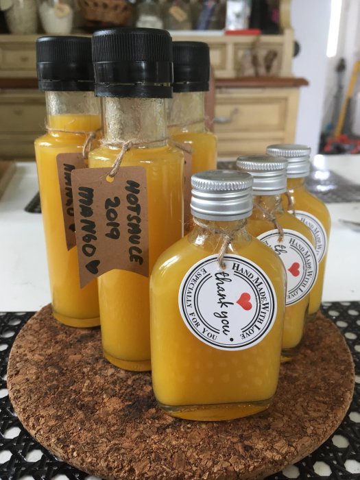 Flaskor med hemgjord Aji Mango het sås, etiketter med texten 'Handmade with love thank you.'