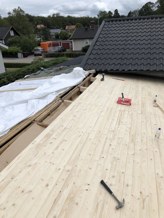 Nyinstallerad råspont och påbörjad takpapp på ett hus under renovering.