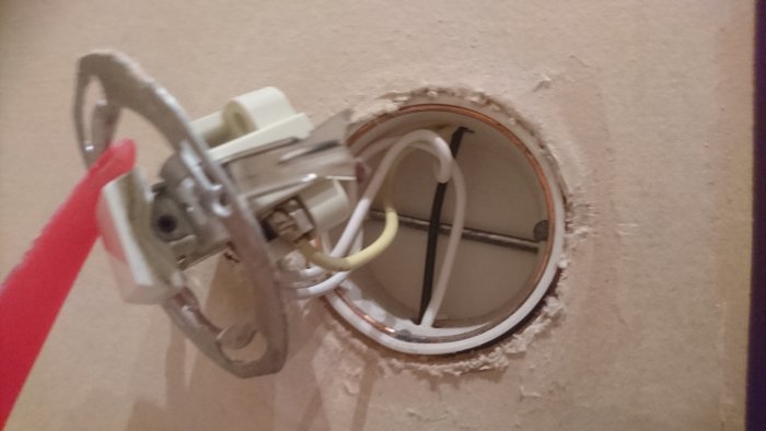 Elektrisk installationsdosa i vägg med synliga kablar och monteringsdetaljer, behöver justering för passning.