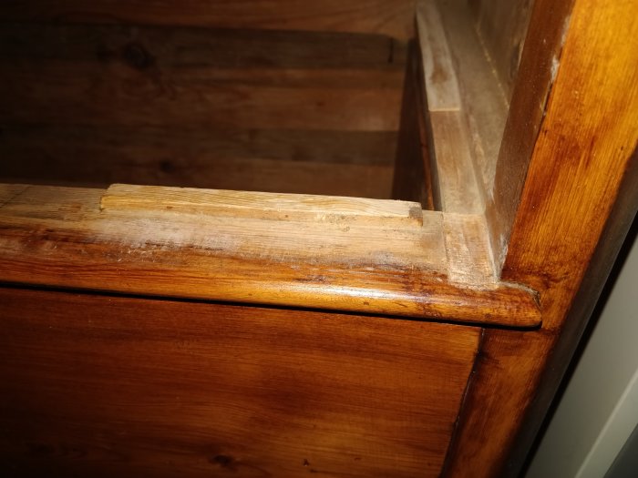 Detaljbild på återanvänd trädetalj och laxstjärtssammanfogning i en gammal byrå under dödstädning.