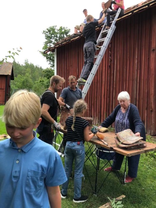 Familj och vänner hjälper till med takomläggning, några på stege och andra förbereder material.