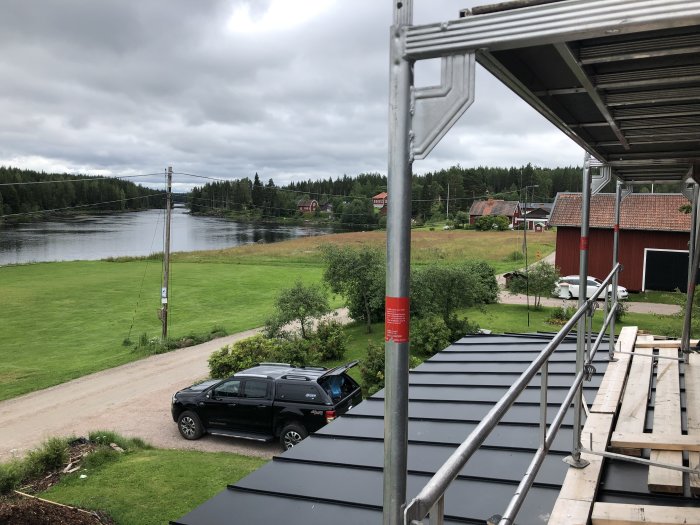 Uppbyggnad av altantak med synlig ställning och utsikt över en sjö i Dalarna, samt en telefonstolpe.