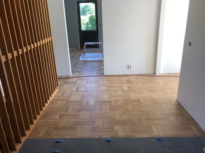Hall med nytt hårdvaxoljat ekgolv och en befintlig furuspaljé vägg, entrédörr i bakgrunden.