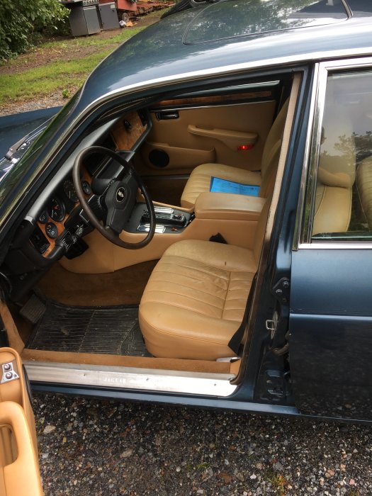 Interiör av en klassisk Jaguar XJ6 med beige lädersäten och trämönstrad instrumentbräda.