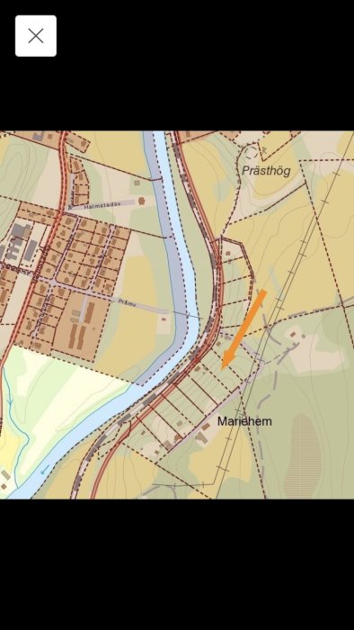 Kartbild över en sluttnings-tomt markerad med en orange pil, omgiven av vägar och terrängkonturer.