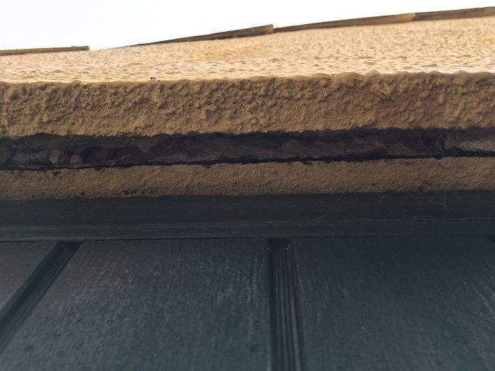 Rikkoutunut rappaus teollisuusoven yläpuolella; näkyvissä ruostunut I-palkki rakenteen sisällä, vaatii korjausta ennen katon uusimista.